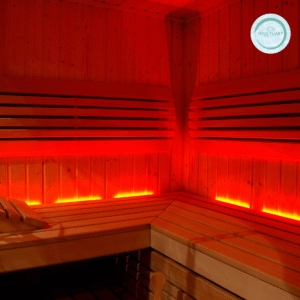 A wooden sauna room with warm red lighting under the benches, creating a cozy atmosphere. The walls and benches are made of smooth wood, and a round Soul Tuary logo is visible on the wall.